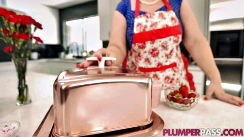 Chubby housewife in frilly red apron teasing curves over kitchen counter with toaster