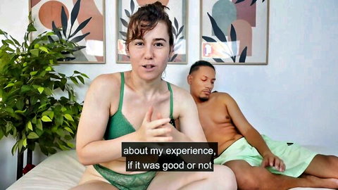 Curvy white woman in green lingerie talks about sex experience with shirtless black man lying beside her on bed