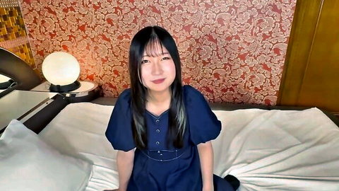 Seductive Asian babe with bangs in navy blue dress on bed