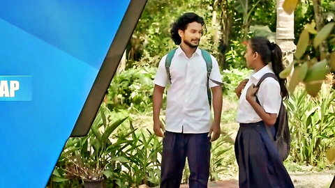 Indian schoolgirl in uniform skirt talking to curly-haired boy in lush green garden