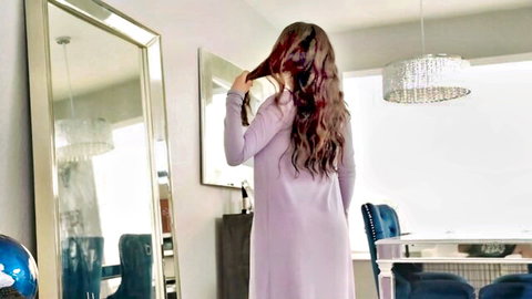 Sophia Leone in form-fitting purple lingerie, back view pulling hair in mirror