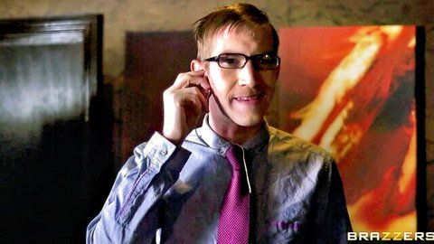 Handsome blonde businessman in glasses and pink tie adjusts earpiece smiling in Brazzers scene