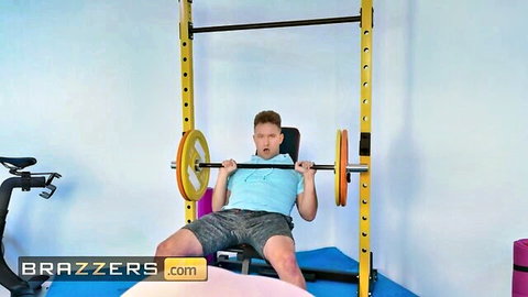Muscular guy in tight shorts bench pressing heavy barbell in gym