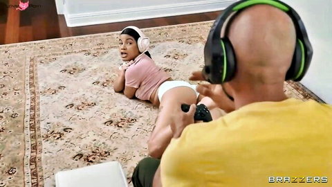Ebony babe in white panties lies on floor teasing bald gamer's crotch with ass up while both wear headsets