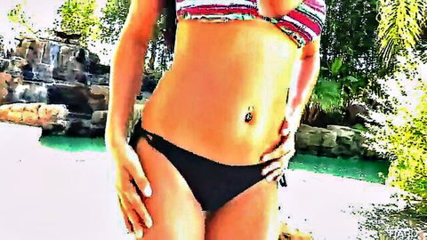 Sexy brunette in striped bikini top and black bottoms flaunting pierced navel by tropical pool