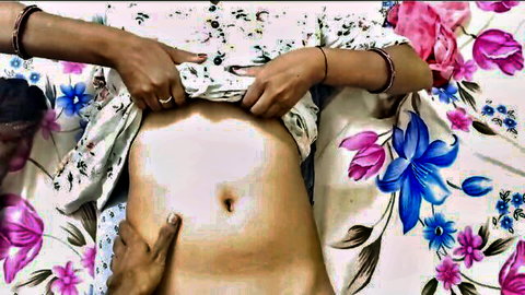 South Asian woman's bare belly and navel exposed and caressed by hands on floral bed