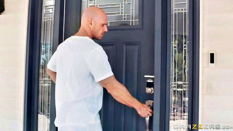 Bald muscular man in white t-shirt opening dark front door outdoors at Brazzers house
