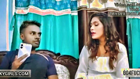 Indian boyfriend holding phone smiling with hot girlfriend in white dress on bed