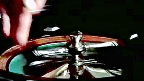 Blurry closeup of spinning roulette wheel with hand tossing chips on casino table