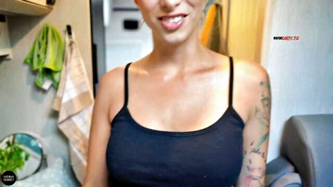Tattooed blonde with big tits smirks tongue out teasing cleavage in tight black tank top