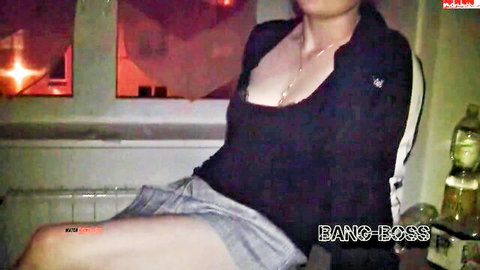 Busty blonde in low-cut black top flashes deep cleavage and spreads legs in shorts on office windowsill
