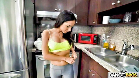 Tia Cyrus in sheer green tank top and tight gray leggings, teasing pose