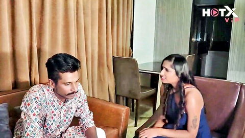 Sexy Indian couple cuddling intimately on leather couch in bedroom