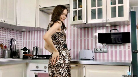 Lucy Shy in leopard print dress, teasing pose in kitchen