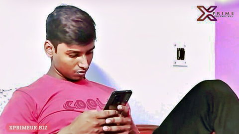 Young Indian man in pink shirt checking phone casually
