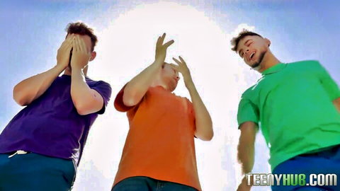 Three playful young guys posing with hands over eyes and up under bright sun in colorful shirts