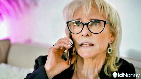 Mature blonde granny in glasses seductively talking on phone with open mouth