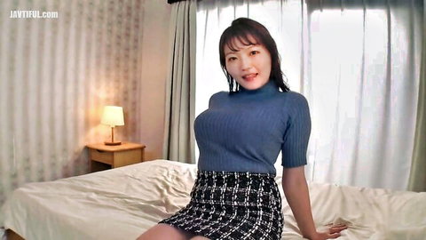 Busty Japanese babe smiling in tight blue turtleneck sweater and checkered mini skirt on bed