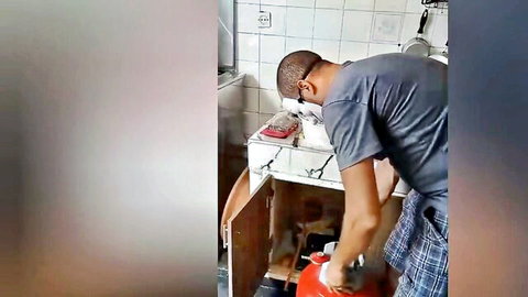 Amateur handyman in plaid pants fixing sink in bathroom