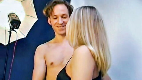 Shirtless hunk smiles intimately at busty blonde girlfriend in black bra straps