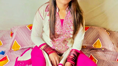 Naughty Indian teen in white embroidered salwar kameez and pink pants sitting seductively on bed