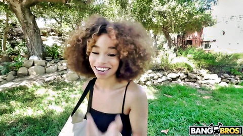 Curly haired ebony teen smiling playfully outdoors in tight black tank top Bang Bros
