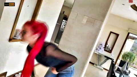 Redhead babe in sheer black mesh top exposing huge tits and tight jeans ass in home tease.