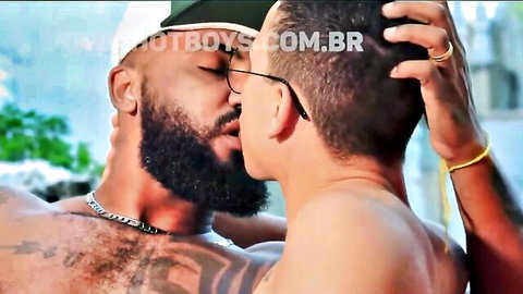 Two muscular bearded men passionately kissing shirtless outdoors showing tattoos and abs