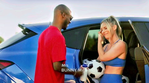 Blonde MILF Bunny May in tight blue sports bra holding soccer ball next to BBC stud by blue SUV