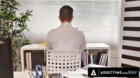 Brunette short-haired man in white shirt sits at modern office desk in gay scene