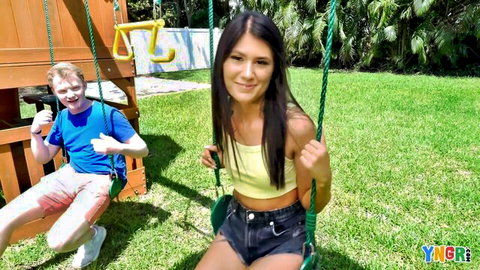 Young skinny brunette with small tits in yellow tube top and tiny denim shorts smiling on backyard swing