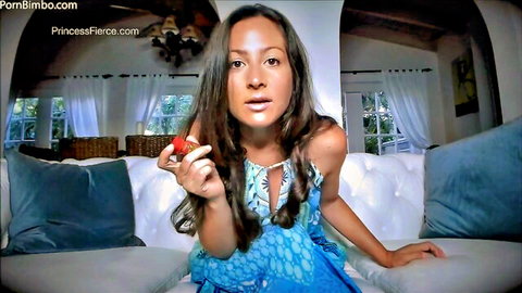 Sexy brunette princess fierce in blue dress teasing plump lips with juicy strawberry