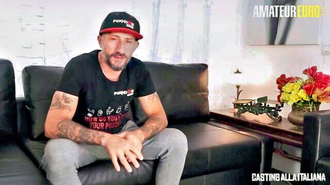 Tattooed mature man in Porn cap and shirt sits on couch for amateur euro casting
