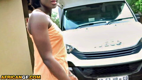 Ebony babe in tight orange tube dress posing seductively by white JACCO van outdoors