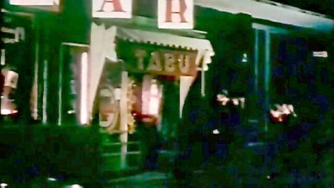 Vintage retro Tabu nightclub entrance at night with glowing green lights and shadowy figures