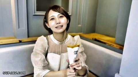 Cute short-haired Asian babe in sheer white blouse holding waffle cone smiling in cafe