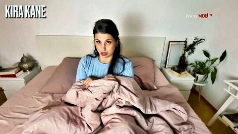 Kira Kane brunette beauty pouting seductively on bed in tight blue top teasing big tits