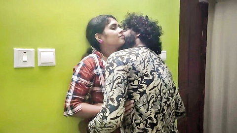 Passionate Indian couple kissing deeply against green wall in romantic embrace