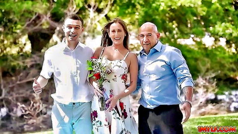 Stepmom in floral white dress with stepson and man outdoors holding roses
