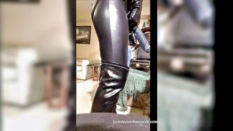 Woman in shiny black latex pants and boots posing for kinky pegging scene