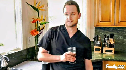 Van Wylde in black scrubs holding water glass in kitchen scene