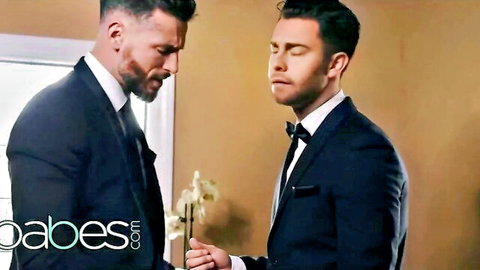 Two suited men in intense intimate moment with white lily flower