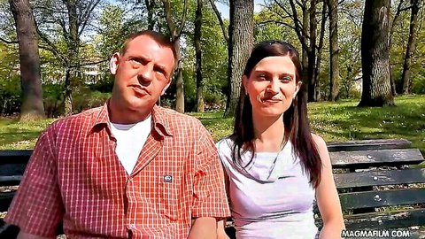 Amateur skinny couple husband and wife smiling together on park bench outdoors