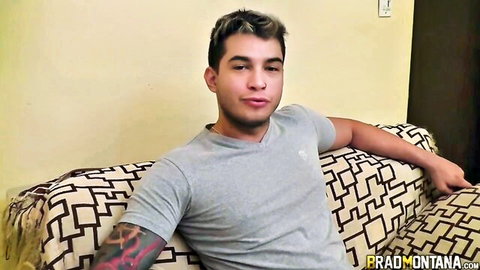 Brad Montana lounging seductively in gray V-neck shirt with tattooed arm