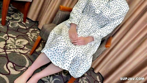 Asian woman in polka dot dress sits modestly, teasing new kinky look