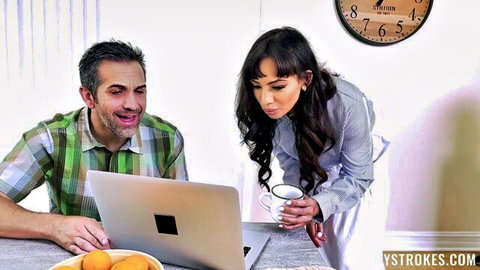 Brunette MILF leans over smiling man viewing laptop screen while holding coffee mug