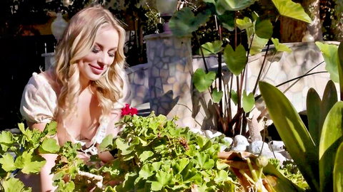 Sexy blonde with deep cleavage gardening in low-cut top outdoors