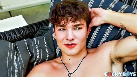 Sexy curly-haired twink lounges shirtless outdoors exposing toned chest and hairy armpit