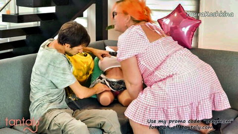 Curvy redhead step-mom in pink dress straddling step-son on couch