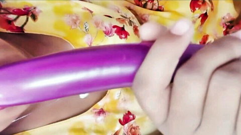 Busty babe in floral dress holds thick purple dildo between her massive cleavage tits